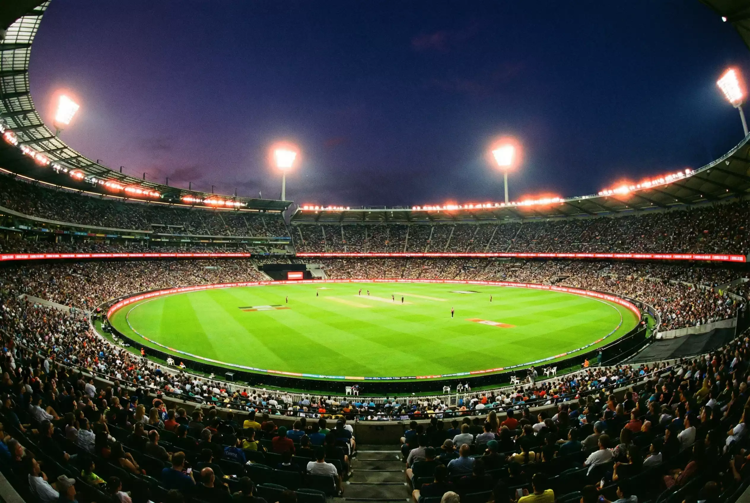Vollbesetztes Cricket-Stadion während eines T20-Spiels bei Abendbeleuchtung